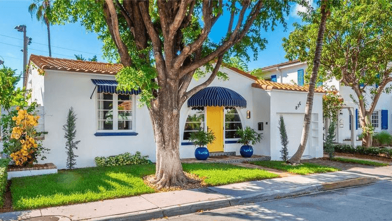 A one story Art Deco home in white with navy trim and tiled roof with an old growth oak in front, located at 1234 House Lane, Langsley, VA 90210 and listed for $650,000.